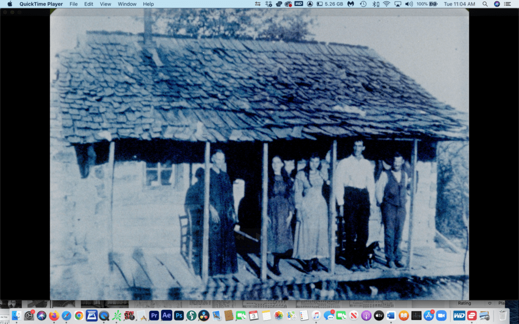 A group of people standing under the shade of an old house