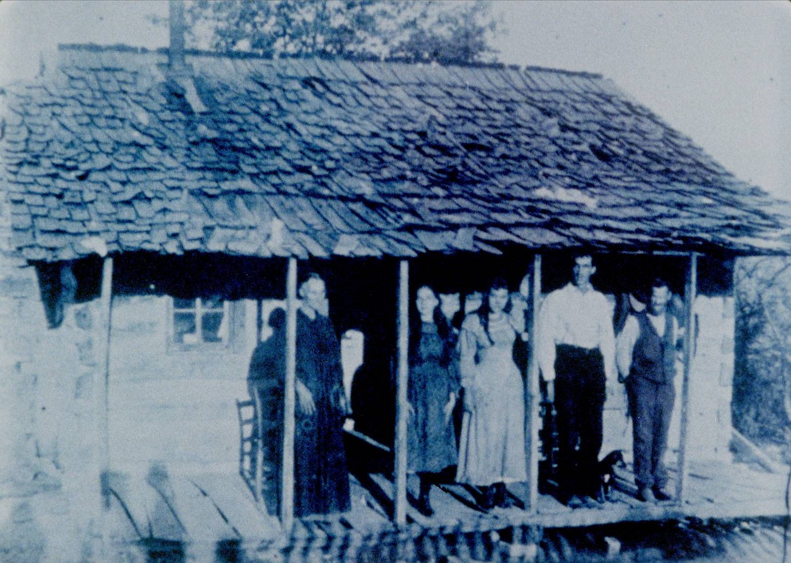 A group of people standing on the porch of a house.