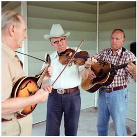 Three men are playing their instruments in a room.