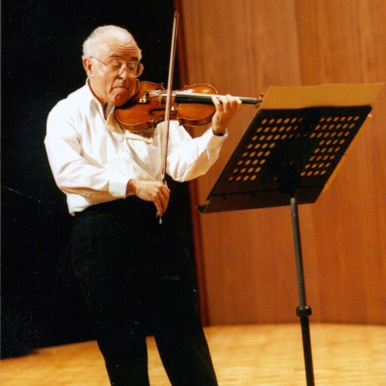 A man playing the violin in front of a sheet music stand.
